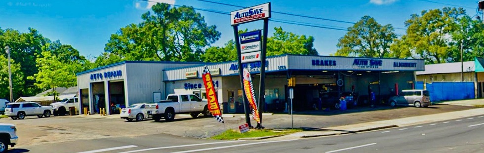 Storefront, parking lot, and open service bays with cars at Auto Save Tire and Service Center in Pensacola, FL